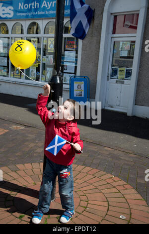 Le elezioni generali del 2015. Largs, Ayrshire, in Scozia. Piccolo Ragazzo con palloncino SNP e saltaire (bandiera scozzese) al di fuori del negozio di sì. Foto Stock