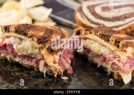 Ruben classico panino sulle pumpernickel swirl pane di segale. Un abbondante pasto con un lato della salamoia e trucioli Foto Stock