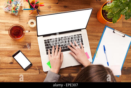 Giovane donna che lavorano con il computer portatile collocato sulla scrivania in legno con schermo vuoto per il testo. Colpo da vista aerea Foto Stock