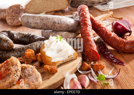 Varie salsicce, carne, pane con lardo, Brawn e scratchings su sfondo di legno. Tradizionale culinaria piatto a base di carne. Foto Stock