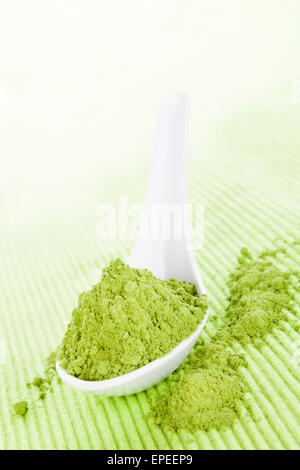 Detox. Polvere di Wheatgrass sul cucchiaino di colore bianco su sfondo verde. Medicina alternativa. Foto Stock