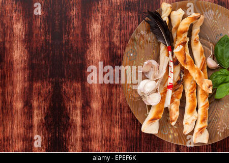 Pizza grissini sul piatto di legno su legno marrone scuro dello sfondo con copia spazio. Delizie pizza italiana di mangiare. Foto Stock