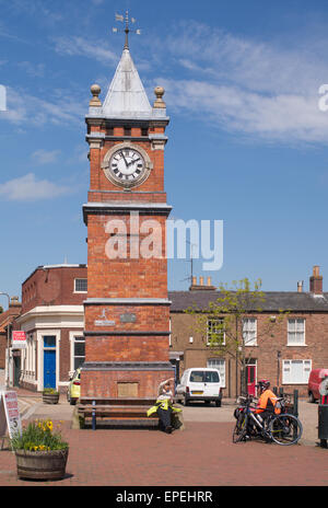 I ciclisti seduta parlando a torre dell Orologio Wainfleet market place, Lincolnshire, England, Regno Unito Foto Stock