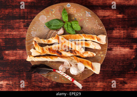 Pizza grissini sul piatto di legno su legno marrone scuro dello sfondo. Delizie pizza italiana di mangiare. Gastronomia sfondo. Foto Stock