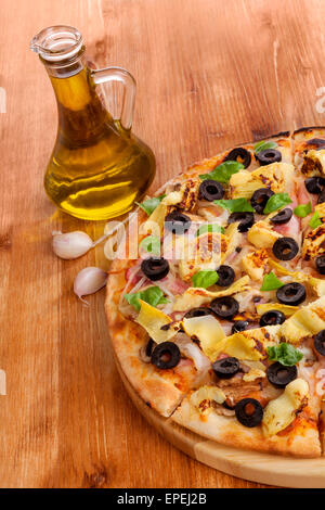 Fresh pizza deliziosa, olio extra vergine d'oliva e aglio su sfondo di legno. Mangiare Pizza sfondo. Foto Stock