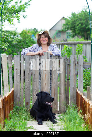 Donna felice nel giardino con la sua labrador Foto Stock