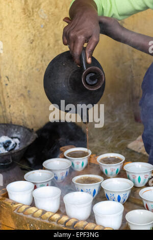 Donna etiope eseguendo una tradizionale cerimonia di caffè, versando acqua calda nero caffè in tazze, Etiopia. Impostazione interna. Foto Stock