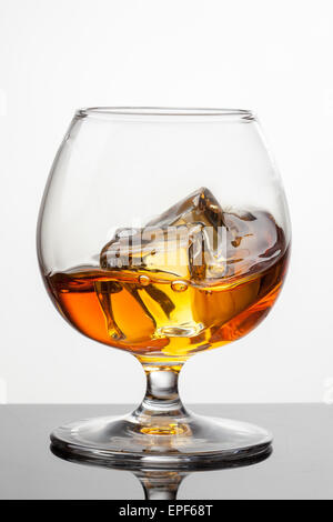 Splash di whiskey con ghiaccio in vetro isolato su sfondo bianco. Foto raw Foto Stock