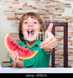 Little Boy di mangiare un cocomero al tavolo Foto Stock