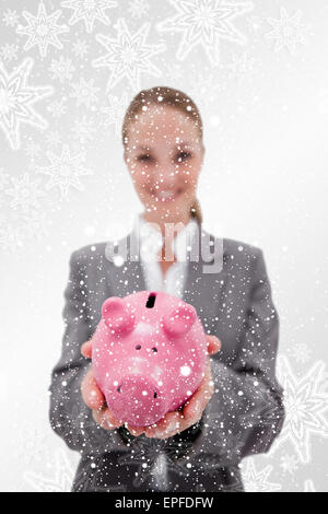 Immagine composita di salvadanaio essendo tenuto dalla sorridente dipendente della banca Foto Stock