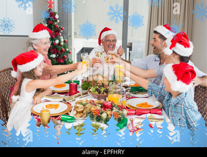 La famiglia in cappelli di Babbo Natale tostatura di bicchieri di vino al tavolo da pranzo Foto Stock