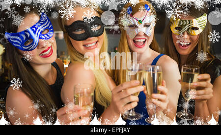 Immagine composita di sorridere amici holding champagne indossare le maschere Foto Stock