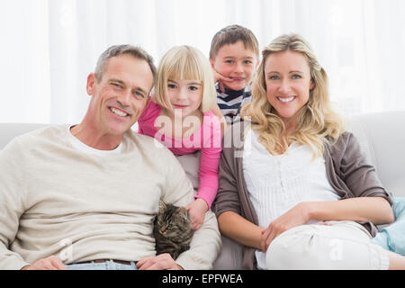 La famiglia felice seduta con pet kitten insieme Foto Stock