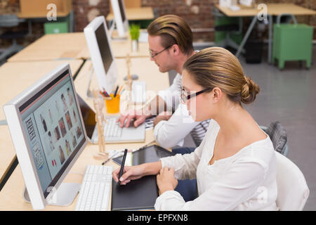 Concentrato casual editor di foto utilizzando il digitalizzatore in office Foto Stock