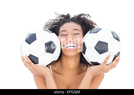Bella ragazza con acconciatura afro sorridente in telecamera tenendo palloni da calcio Foto Stock