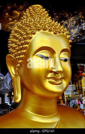 Bangkok, Thailandia: il volto di un dorato grande statua del Buddha in un negozio specializzato in buddista di oggetti religiosi Foto Stock