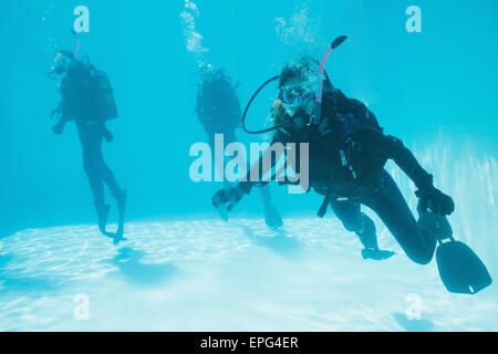 Gli amici sulla formazione di scuba immersi nella piscina uno che guarda alla fotocamera Foto Stock