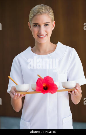 Sorridente terapista di bellezza tenendo il vassoio di trattamenti Foto Stock