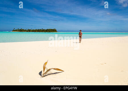 Donna che cammina sulla spiaggia bianca in posizione idilliaca scenic sullo sfondo di un mare turchese e remota isola deserta. Aitutaki, Isole Cook. Foto Stock
