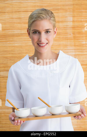 Sorridente terapista di bellezza tenendo il vassoio di trattamenti Foto Stock