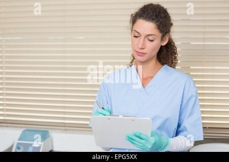 Dentista in blu scrubs iscritto negli appunti Foto Stock