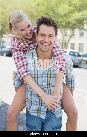 Giovane Hip uomo dando la sua ragazza bionda una piggy back Foto Stock