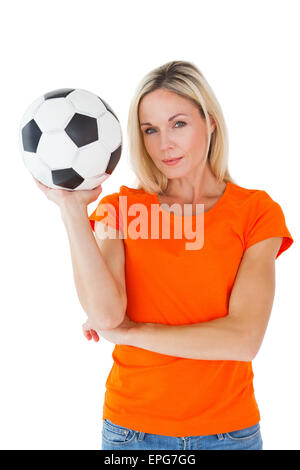 Appassionato di calcio tenendo palla in arancione tshirt Foto Stock