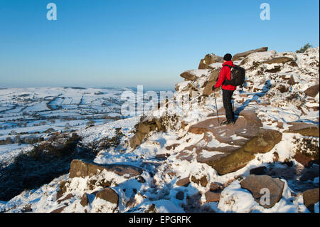 Walker in snow ammirando vista di Bosley Cloud & Cheshire dal scarafaggi, Peak National Park, Staffordshire, Inghilterra. Foto Stock