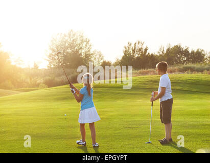 Casual i bambini in un campo da golf holding golf club Foto Stock