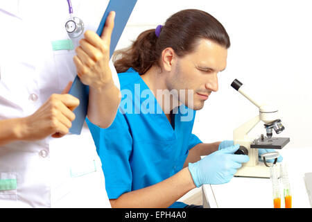 Scienziato guardando attraverso un microscopio Foto Stock