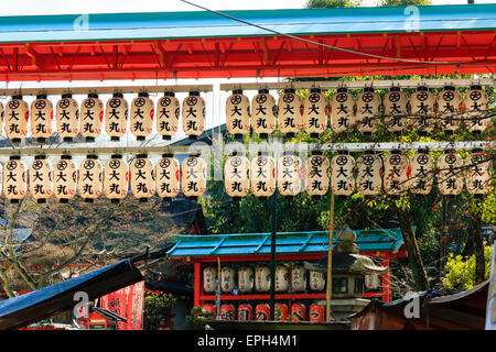 File di chochin, lanterne di carta, appese da una porta di vermiglio torii sull'ingresso si avvicina alla parte principale del santuario di Yasaka a Kyoto, Giappone. Foto Stock