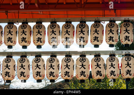 File di chochin, lanterne di carta, appese da una porta di vermiglio torii sull'ingresso si avvicina alla parte principale del santuario di Yasaka a Kyoto, Giappone. Foto Stock