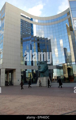 Una statua in bronzo del capo di un uomo circondato da un moderno, vetro edificio per uffici. Foto Stock