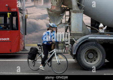 Donna ciclista inizia a sorpassare un fermo betoniera camion nella Shoreditch, Londra. Foto Stock