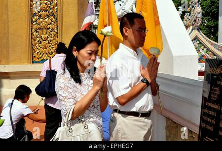 Bangkok, Thailandia: devota Thais buddista tenendo i fiori di loto pregare presso un santuario terrazza presso il Royal Wat Boworniwet Foto Stock