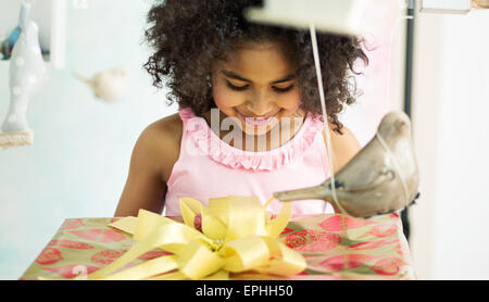 Adorabile ragazza giovane aprendo il regalo di compleanno Foto Stock