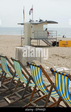 Sedie a sdraio sul lungomare a Bournemouth nel Dorset. Nel frattempo un bagnino si siede nella sua torre. Foto Stock
