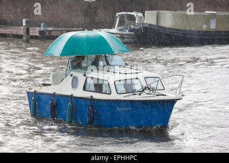 Piove di Amsterdam. Piccola imbarcazione, piccolo cabinato in estate improvvisa pioggia con grande ombrellone in Amsterdam canal Foto Stock