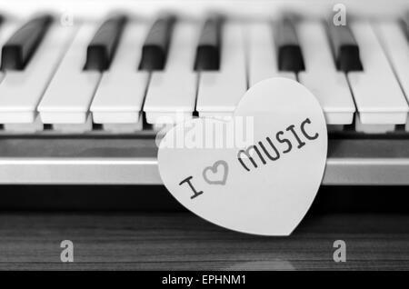 Cuore di carta sulla tastiera di pianoforte in bianco e nero e a colori bianco Foto Stock