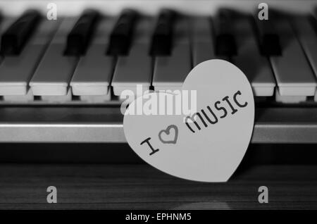 Cuore di carta sulla tastiera di pianoforte in bianco e nero e a colori bianco Foto Stock