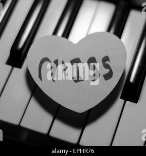 Cuore di carta sulla tastiera di pianoforte in bianco e nero e a colori bianco Foto Stock