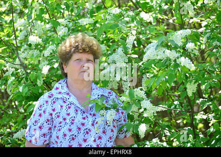 Malinconici donna anziana in primavera la natura con fiori di ciliegio Foto Stock