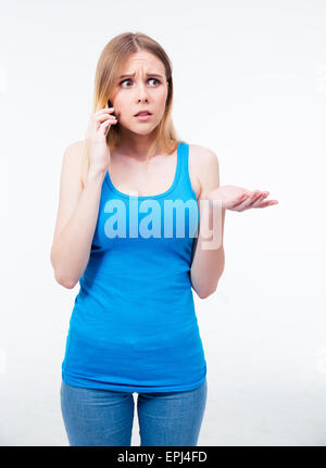Giovane donna appena ascoltato qualcosa che le sue preoccupazioni sul suo telefono cellulare su sfondo grigio. Guardando lontano Foto Stock