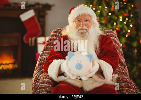 Sorridente santa offrendo salvadanaio Foto Stock