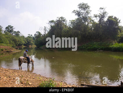 Panama, Provincia di Darien, Filo del parete tallo, Embera Tribe Uomo a cavallo sulle rive del Rio Chucunaque Foto Stock