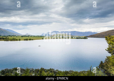 Lone barca sul Lago Wanaka con il sud delle Alpi in background. Otago, Isola del Sud, Nuova Zelanda Foto Stock