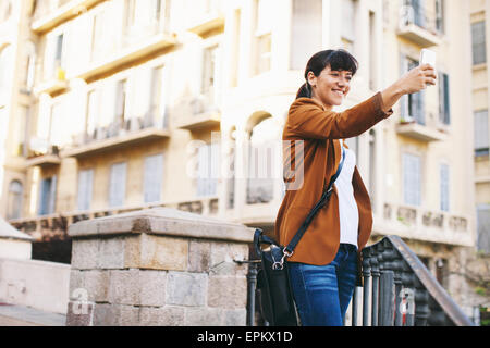 Spagna, Barcellona, sorridente imprenditrice tenendo selfie con lo smartphone Foto Stock