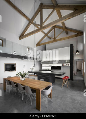 Tavolo da pranzo in legno nero e moderne unità di isola in grande, piano aperto, soffitto alto cucina/sala da pranzo, Cat Hill Granaio, South Yorkshire, Inghilterra, Regno Unito Foto Stock