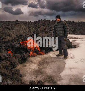 Uomo in piedi dalla lava incandescente flusso, Holuhraun eruzione fissurale, Vulcano Bardarbunga, Islanda Foto Stock