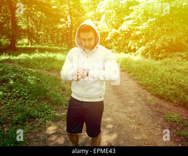 Guida sul sentiero di montagna guardando sport smart watch Foto Stock